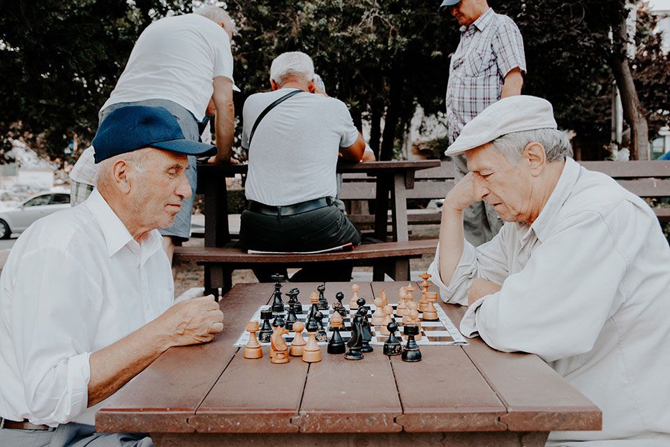 elderly men playing chess outdoors