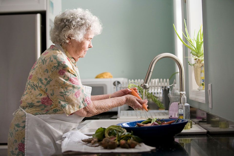 elderly person standing at sink washing dishes