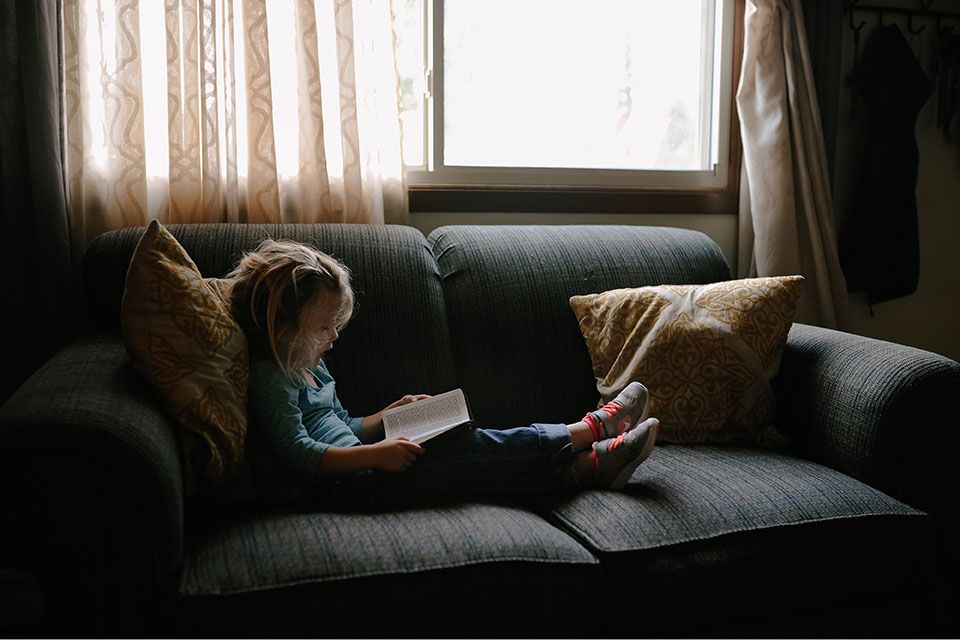 young child sitting on sofa reading