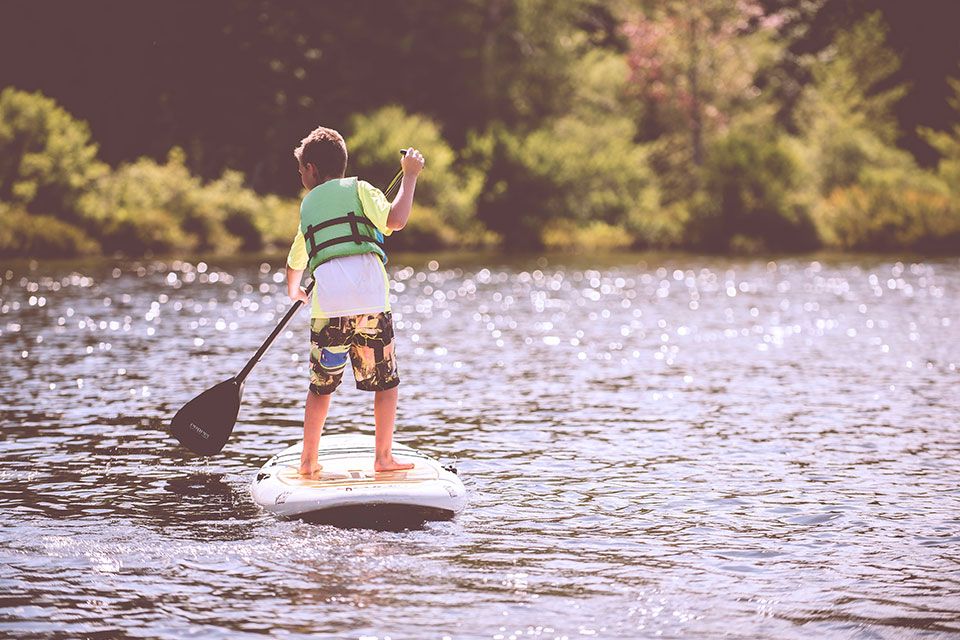 boy paddle boarding at summer camp